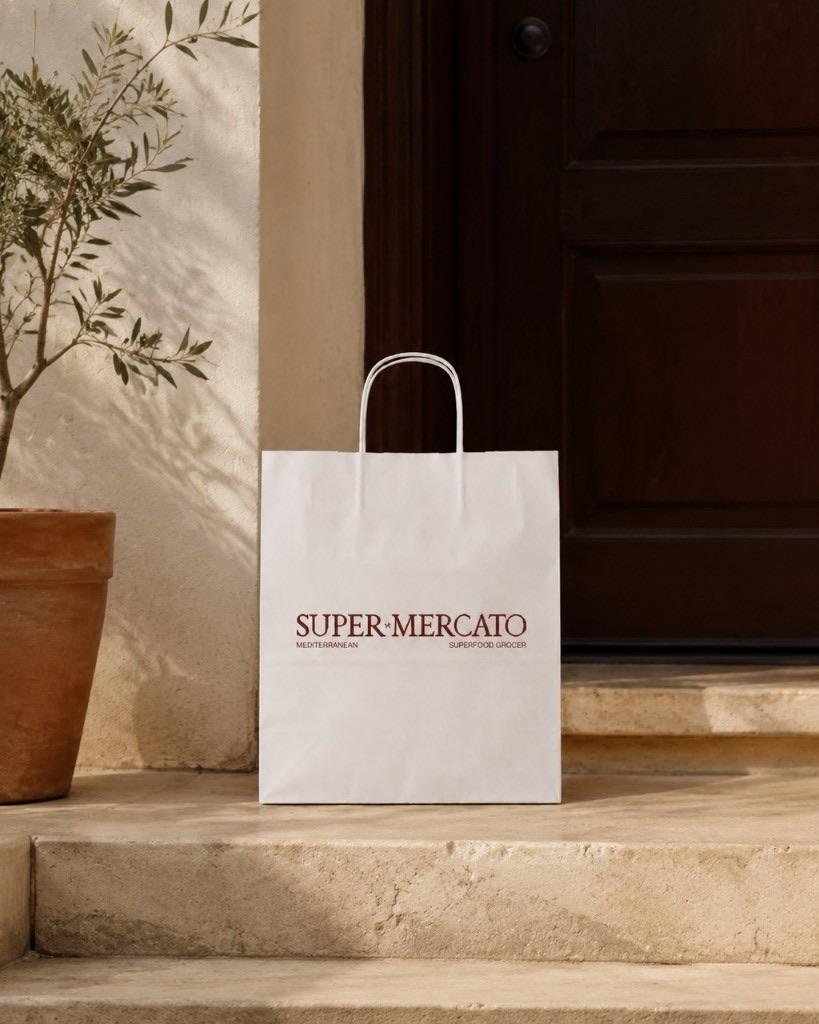 A yoghurt-white Super Mercato delivery bag waiting on a warm stone doorstep.